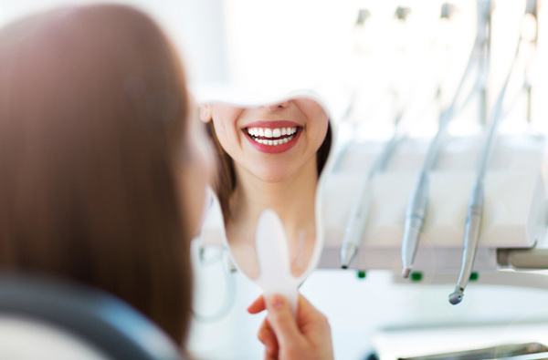 Woman looking at her smile in a mirror in Hackettstown, NJ