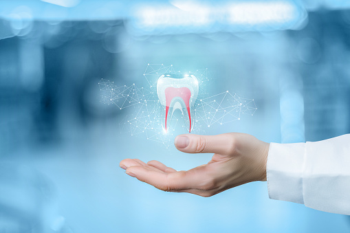 Dentist's hand holding a holographic tooth on a blue background